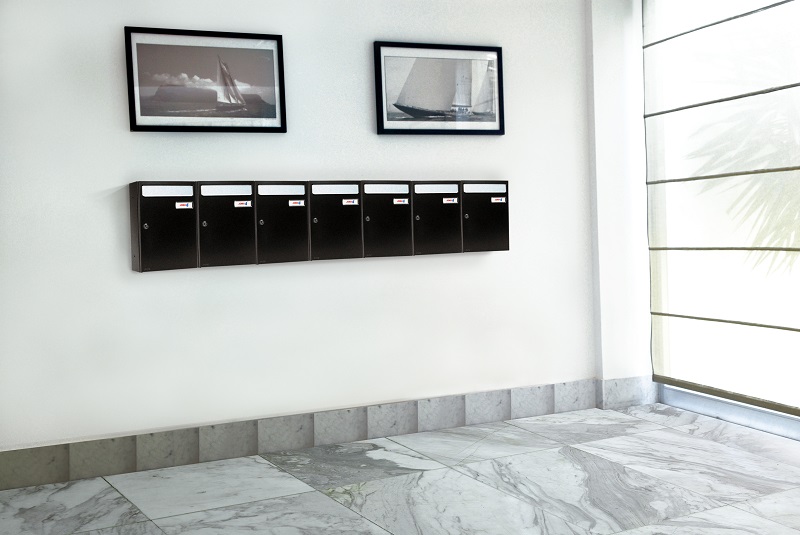 Buzones de interior de superficie verticales atornillados a la pared pintados en color negro con viseras en color plata fabricados por Joma Buzones